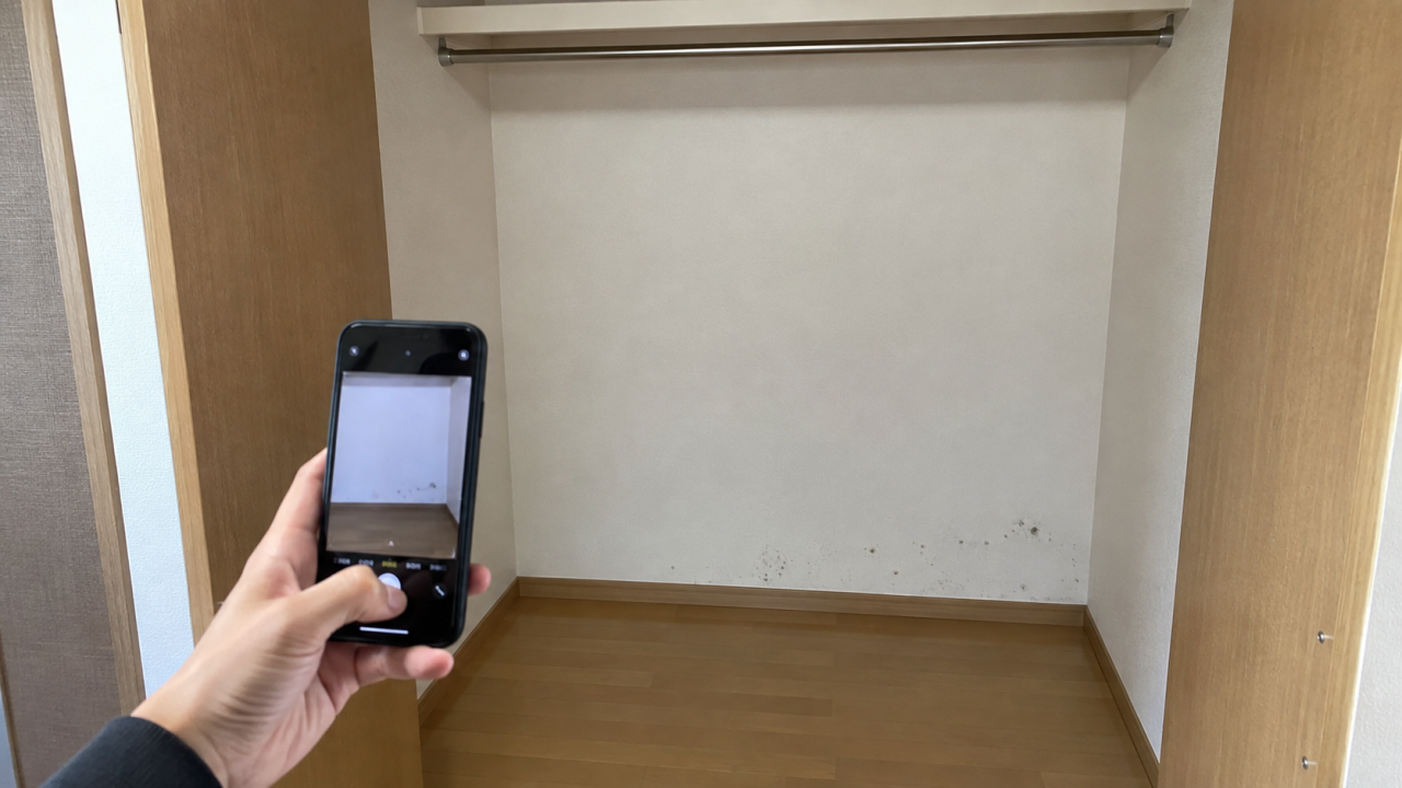 クローゼットの壁の変色を離れた位置から撮影する様子