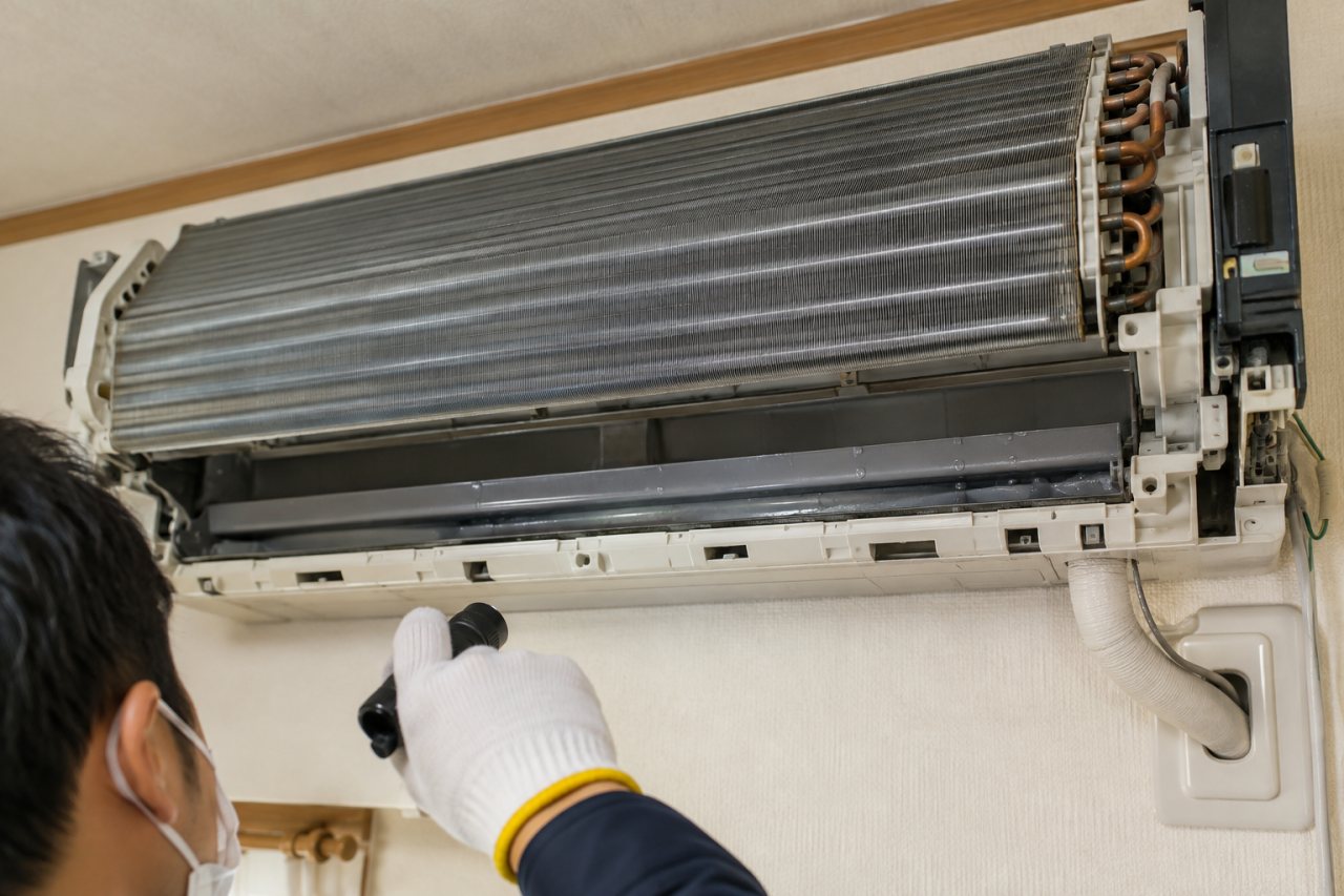 エアコンの熱交換器と排水経路を点検する技術者